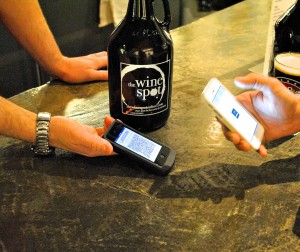 Using a digital wallet, a customer purchases a growler of beer using bitcoin at The Wine Spot. Photo credit: Rebecca E. Groynom